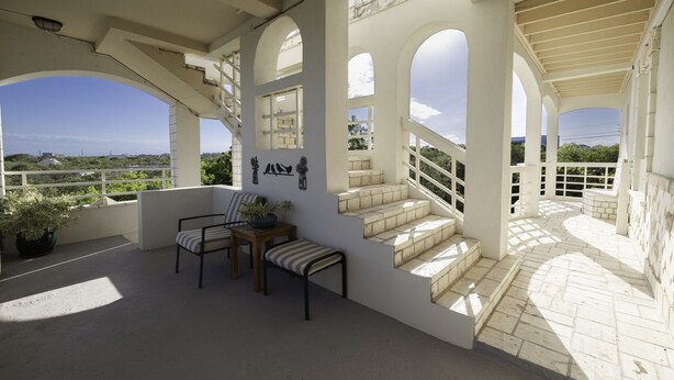 Un espace extérieur abrité, aménagé avec des sièges, un escalier et offrant une vue sur le paysage.