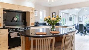 Une cuisine moderne dotée d’un îlot central, d’un four encastré et d’un coin repas avec des chaises.