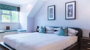Une chambre avec un grand lit, une fenêtre donnant sur un beau paysage et deux tableaux encadrés accrochés au mur.