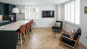 A modern kitchen with a marble countertop, wooden chairs, and pendant lights. - 2Bed 2Bath Stunning Shoreditch Apartment (London)