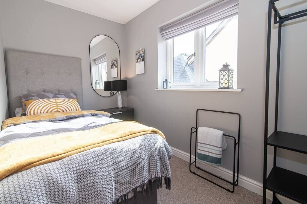 A bedroom with a bed, a bedside table with a lamp, a window with a view, and a towel rack.