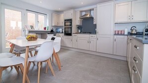 Una cocina moderna con armarios blancos, una mesa de comedor con sillas y vistas al exterior.