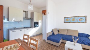 Un ambiente compatto con angolo cottura, divano, tavolo da pranzo e pavimento decorato.