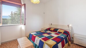 Una camera da letto con un letto, una finestra con tende, una lampada a sospensione e un comodino.