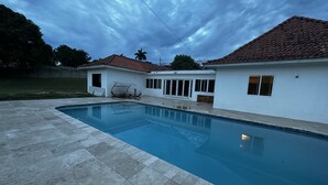 A swimming pool with a tiled deck, a covered seating area, and a building with a tiled roof. - Bay Bliss Retreat home in Ironshore, Montego Bay, less than 10 mins to airport. (Montego Bay)