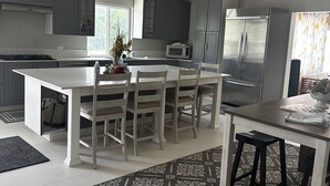 A modern kitchen with a central island, grey cabinets, a stainless steel refrigerator, and a ceiling fan. - Bay Bliss Retreat home in Ironshore, Montego Bay, less than 10 mins to airport. (Montego Bay)