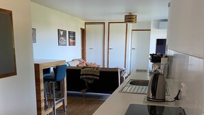 Una cucina moderna con un piano di lavoro, una macchina da caffè e un portatile. È presente un'area pranzo con tavolo e sedie.