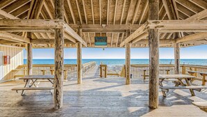 A wooden pier leading to a beach with picnic tables and a sign indicating beach access. - Snowbird Retreat - Private Beach, Heated Pools, Pickleball & Golf! (Destin)