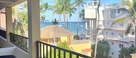 A balcony with a view of palm trees and a beach.