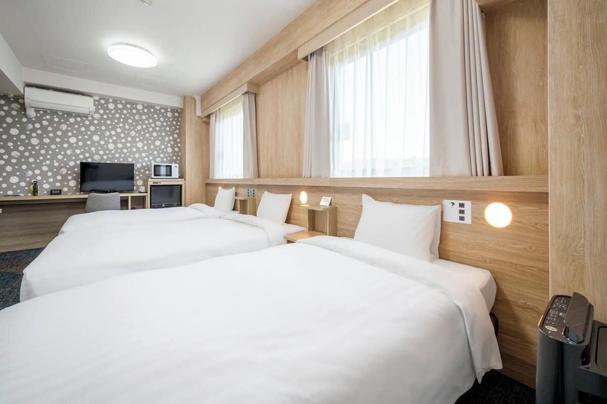 Una habitación de hotel con dos camas, televisión, microondas y cabecero de madera.