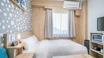 A hotel room with a bed, bedside table, TV, and an air conditioning unit.