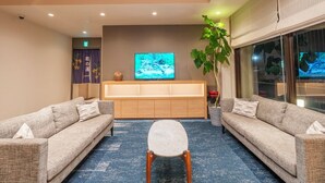 Una sala de estar moderna con sofás, una mesa de centro, un televisor y un ventanal grande.