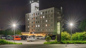 Un hotel de varios pisos con un letrero llamativo, un estacionamiento con varios vehículos y una entrada bien iluminada.