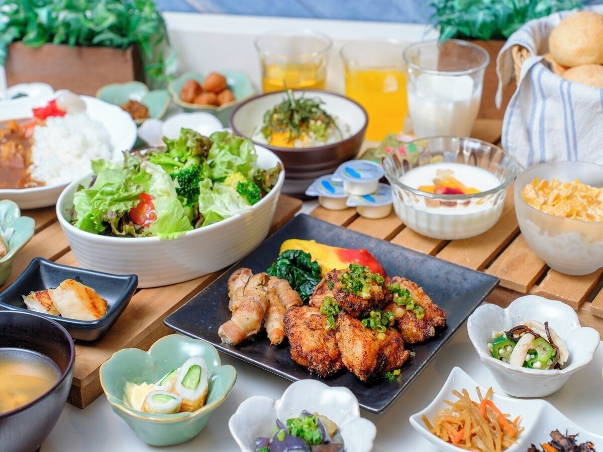 Una variedad de platos, incluyendo una ensalada, pollo frito y varios cuencos pequeños de acompañamientos, sobre una mesa de madera.