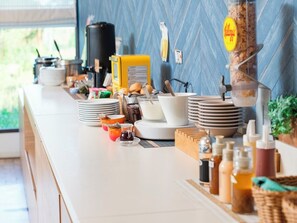 Una barra de desayuno con platos, tazones y una máquina de café apilados.