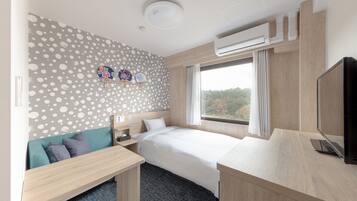 A hotel room with a bed, a desk, a TV, and a window with a view of trees.