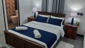A neatly made bed with blue and white bedding, two bedside lamps, and a wooden nightstand. -  Cosy villa with style, luxury and great comfort Close to beach and amenities 

 (Negombo)