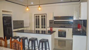 A modern kitchen with a central island, bar stools, and a dining area with a wooden table. -  Cosy villa with style, luxury and great comfort Close to beach and amenities 

 (Negombo)