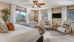 A bedroom with a large bed, a ceiling fan, a TV, and a view of the outdoors. - Cascadia (Cascade)