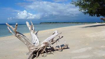Na praia, areia branca, espreguiçadeiras, guarda-sóis
