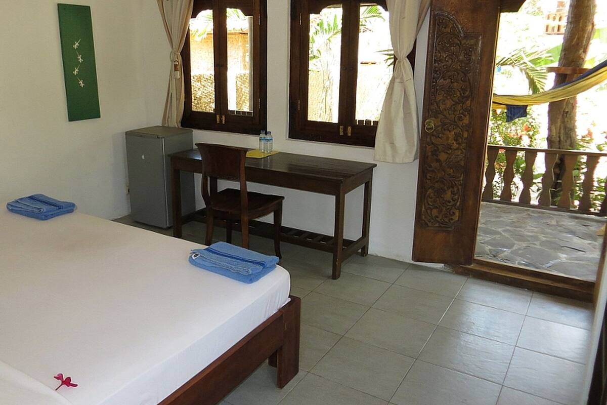 A room with a bed, a desk, a chair, and a small cabinet.