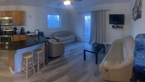 A modern kitchen with a refrigerator, microwave, and stove. There is a dining area with a glass table and chairs. A living room. - 4 Season Cabin great for Summer or Winter activities! 
Excellent Green Space (Marean Lake)