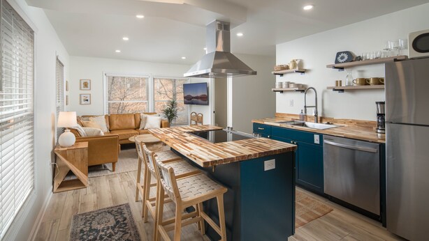 Une cuisine moderne dotée de plans de travail en bois, d’une cuisinière encastrée et d’un réfrigérateur en acier inoxydable.