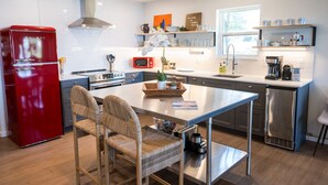 Une cuisine moderne dotée d’un îlot central, d’appareils électroménagers en acier inoxydable et d’un réfrigérateur rouge.