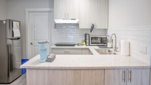 Una cocina moderna con un refrigerador de acero inoxidable, un microondas integrado, un lavaplatos y una cafetera sobre la encimera.