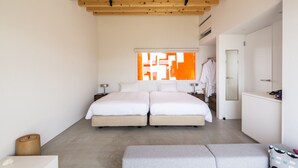 A modern bedroom with two beds, a large window with orange geometric patterns, a wardrobe, and a small seating area. - TUZUMI WAKAYAMA SUSAMI (Susami)