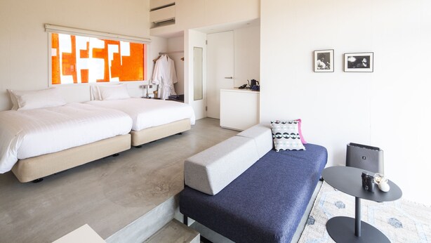 A modern bedroom with a large bed, a smaller bed, a sofa, and a small table. - TUZUMI WAKAYAMA SUSAMI (Susami)