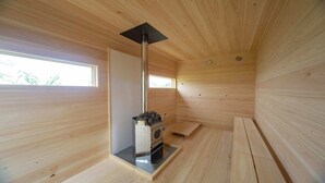 A wooden sauna room with a sauna, a window, and a door. - TUZUMI WAKAYAMA SUSAMI (Susami)
