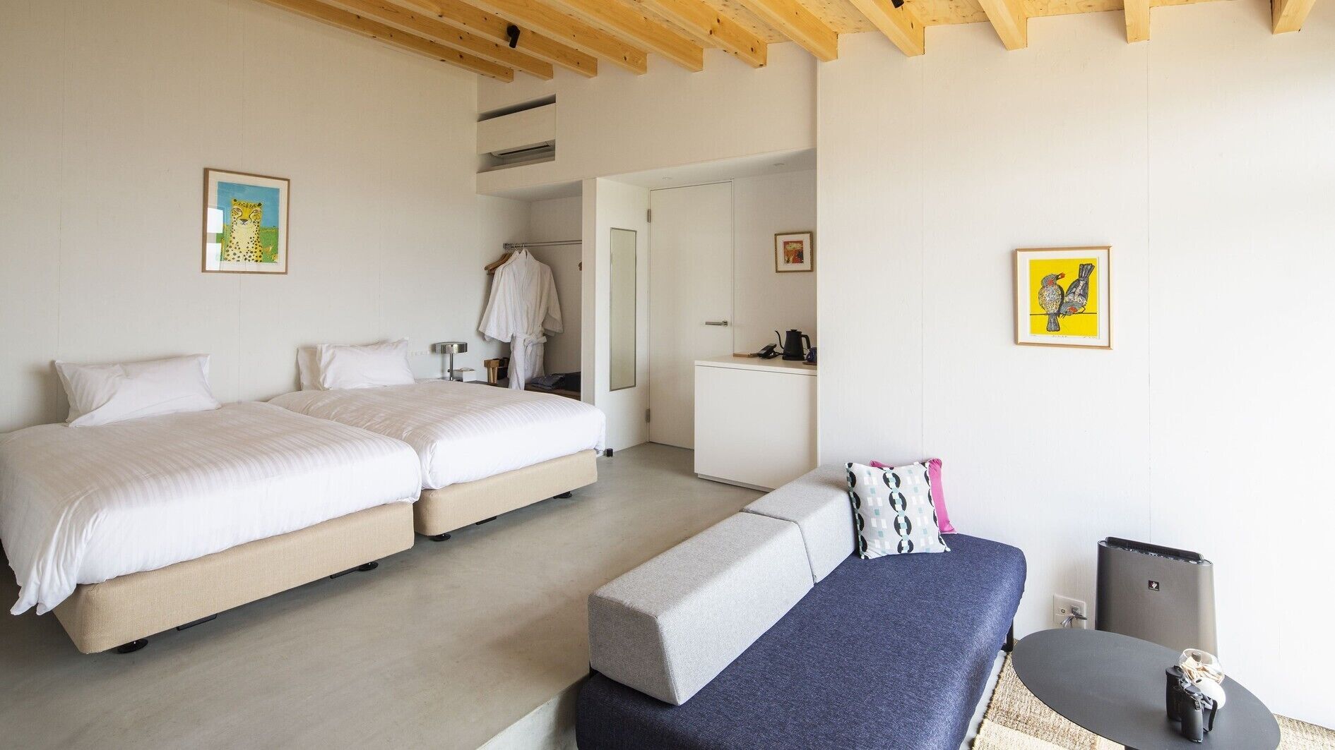 A bedroom with two beds, a desk, and a chair.