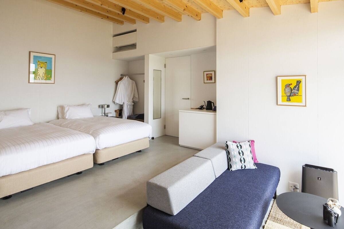 A bedroom with two beds, a desk, and a chair.