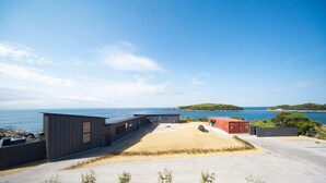 A modern building with a flat roof, a sandy courtyard, and a view of the sea and a distant island. - TUZUMI WAKAYAMA SUSAMI (Susami)