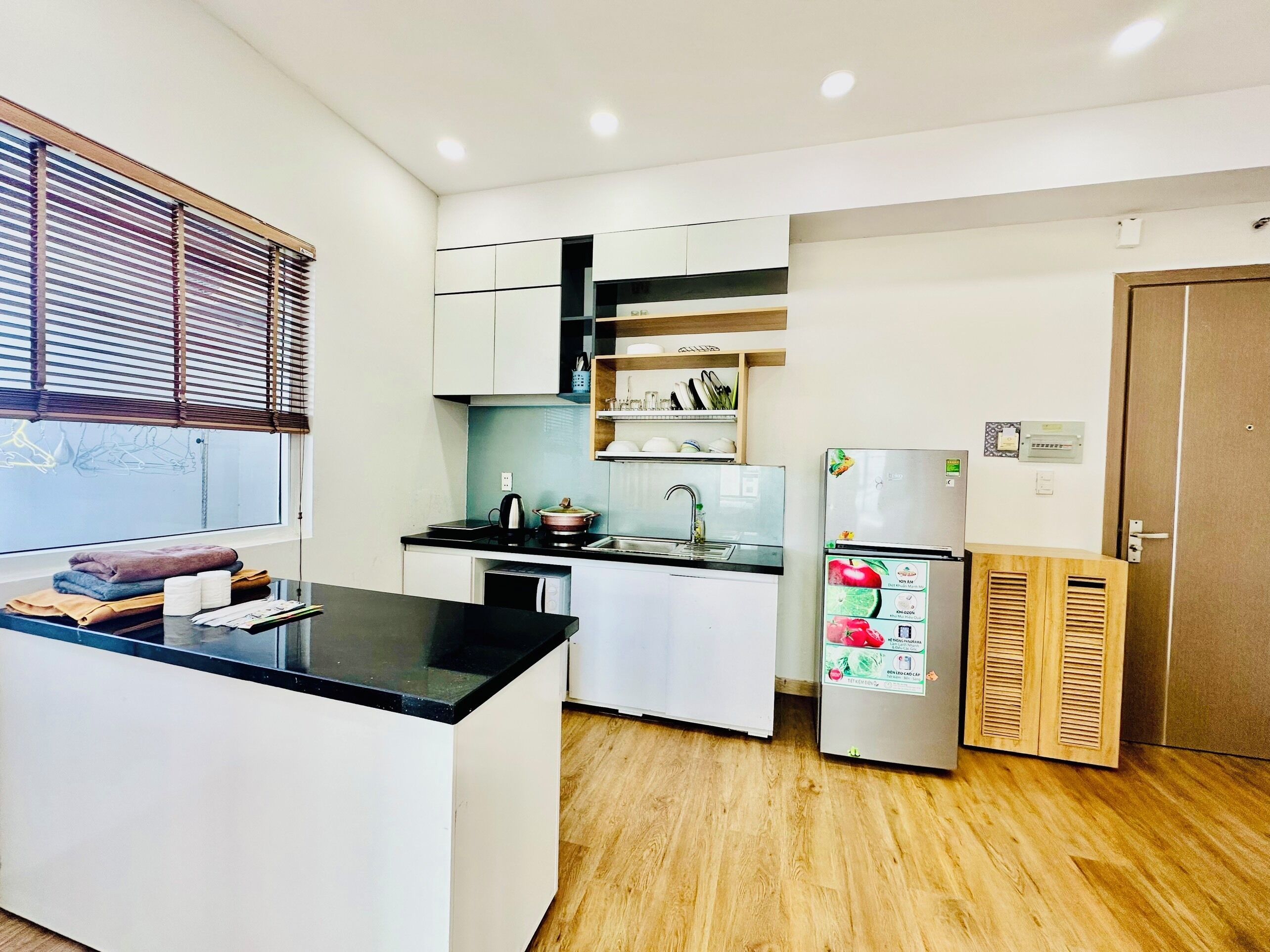 A compact kitchen with white cabinets, a black countertop, a sink, a stove, and a refrigerator.
