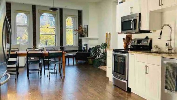 A modern kitchen with white cabinets, a microwave, stove, and a dining area with a table and chairs.