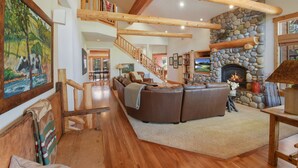 A spacious living area with a stone fireplace, wooden beams, and a large sectional sofa.