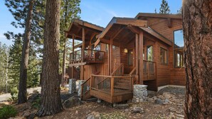 A wooden cabin with a balcony, surrounded by trees.