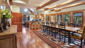 A spacious kitchen with wooden beams, a large island, and a dining area with a patterned rug.