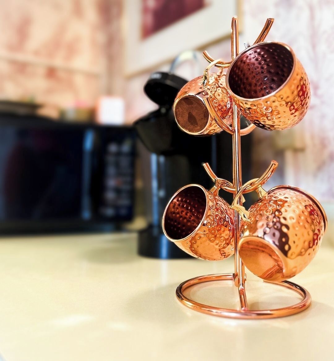 A copper mug stand with three mugs on a kitchen counter.