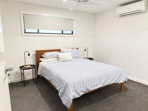 A bedroom with a bed, bedside tables, a ceiling fan, an air conditioning unit, and a window with blinds. - Absolute waterfront modern 4 bedroom property in Woodlands area of Yarrawonga (Yarrawonga)