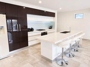 Una cocina moderna con una isla central, armarios oscuros y un ventanal pequeño.