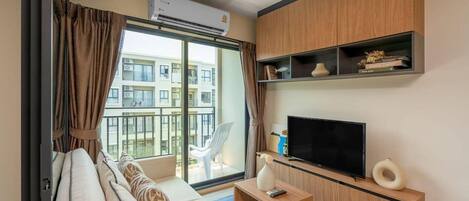 Una sala de estar moderna con un sofá, televisión y estanterías de madera.