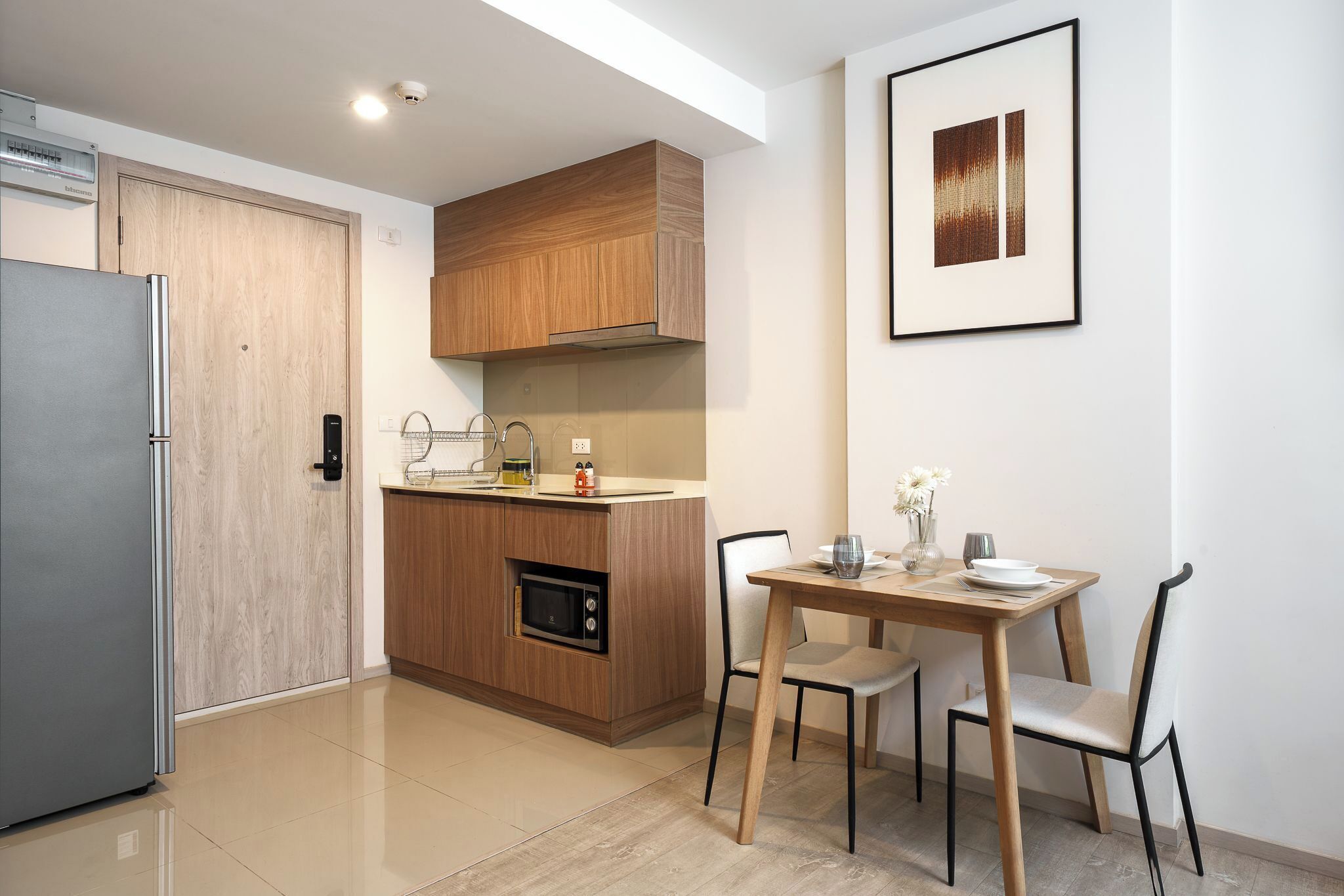 Une cuisine moderne avec des meubles en bois, un four à micro-ondes encastré et un coin repas comprenant une table et des chaises.