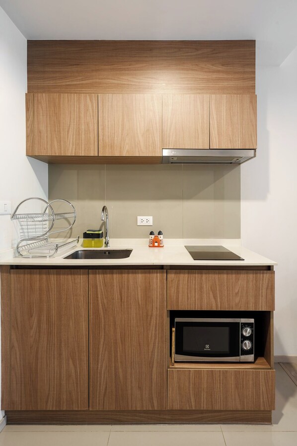 A kitchen with wooden cabinets, a stainless steel sink, a microwave, and a built-in oven.