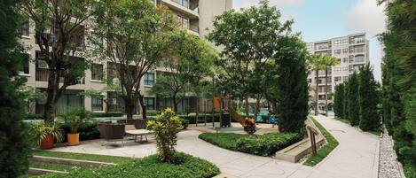 Un patio con un área de juegos, zonas de estar y un sendero.