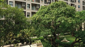 A multi-story residential building with balconies, a swimming pool, and surrounding greenery.