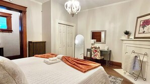 Ein Schlafzimmer mit Bett, einer Deckenleuchte, einer Heizung, einem Spiegel, einem Schreibtisch und einem Kamin.