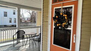 Eine Veranda mit Tisch und Stühlen, eine Tür mit einem Kranz und einer Lampe.